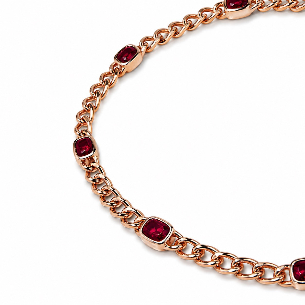 A close up image of a rose gold chain bracelet featuring cushion-cut rubies set in bezels.