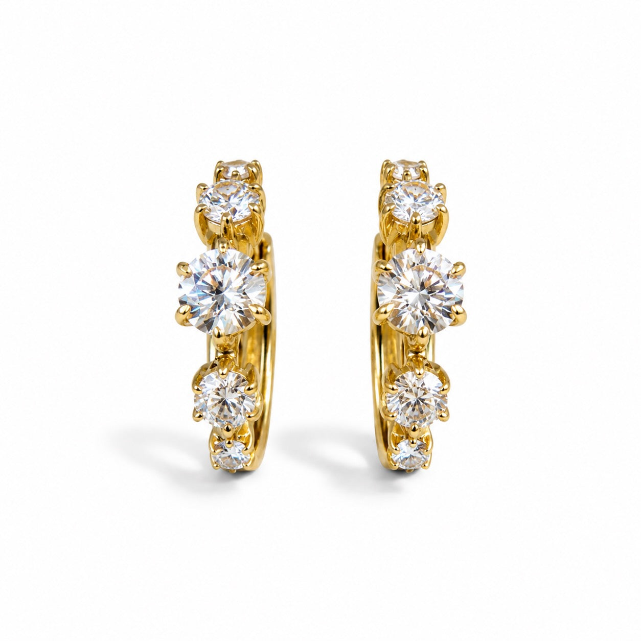 A pair of gold hoop earrings with five round-cut clear gemstones each, set in a vertical arrangement on a clean white background.