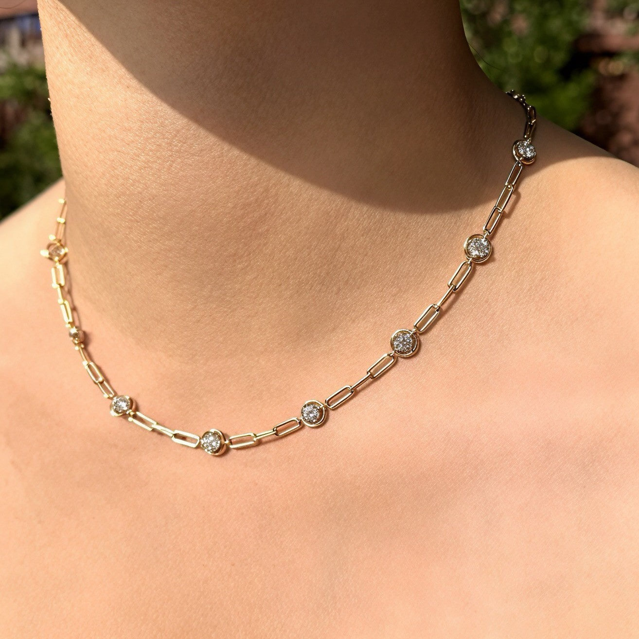 Soriano Custom gold link chain necklace featuring bezel-set round sparkling stones worn on a woman's neck.